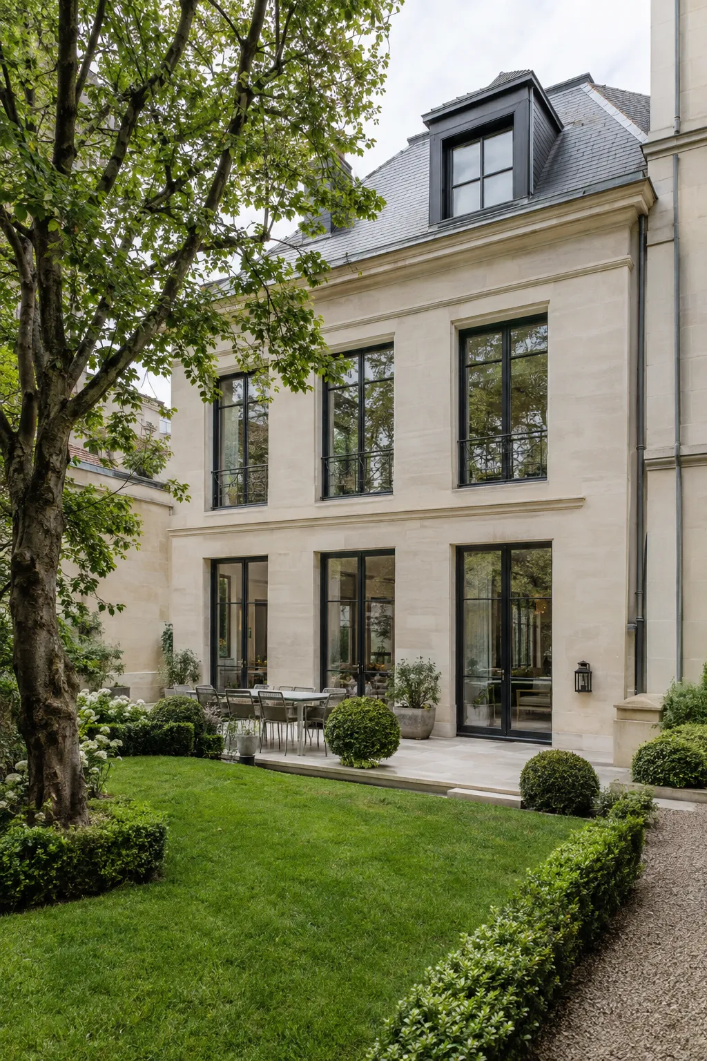 Façade de la villa avec fenêtres en acier noir et jardin arboré